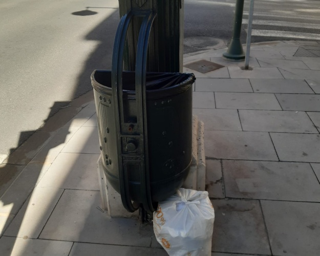Bolsa de basura en la vía pública junto a una papelera