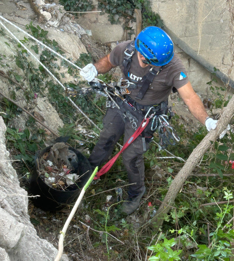 Operari de treballs verticals subjecte per les cordes i equip de seguretat realitzant la neteja
