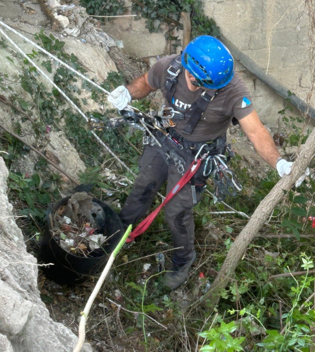 Operario de trabajos verticales sujeto por las cuerdas y equipo de seguridad realizando la limpieza