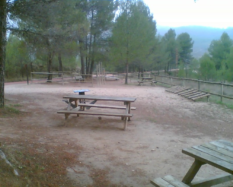 Zona delimitada por valla de madera con  mesas, bancos y aparcabicis 