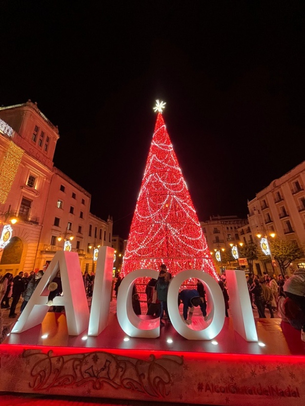 Letras iluminadas de grandes dimensiones de Alcoi con el árbol de Navidad detrás en la Plaça d'Espanya