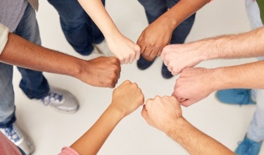 Braços de persones de diferents races amb el puny tancat formant un cercle