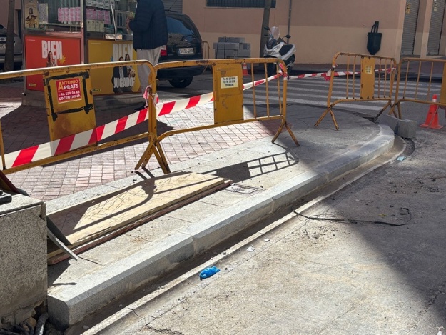 Acera en obras en la calle Camí y vallas impidiendo el paso a la obra