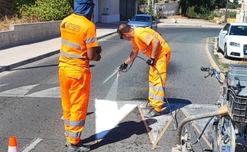 Dos operaris treballen en la senyalització de carreteres