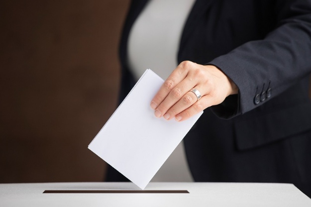 Persona introduint una papereta en una urna de votació
