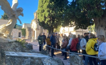 Participants de la visita guiada al cementeri atenent les explicacions del guia