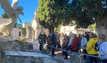Participants de la visita guiada al cementeri atenent les explicacions del guia