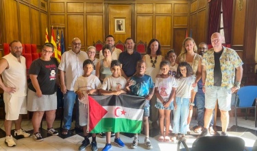 El alcalde, el vicealcalde y la concejala de Infancia posan en el Salón de Plenos con los 5 menores y las familias de acogida con la bandera saharaui