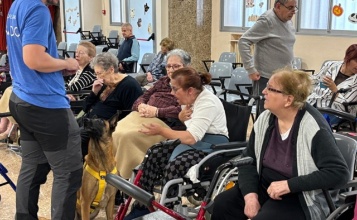 Persones majors interactuant amb la gossa Aire, campiona del món en obediència