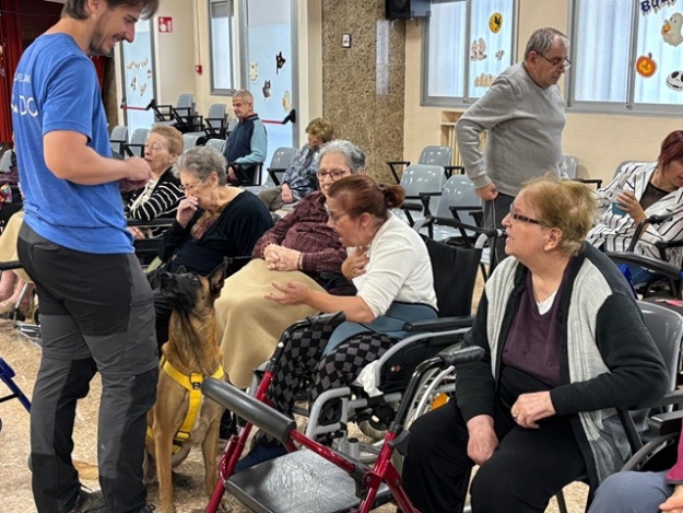 Personas mayores interactuando con la perra Aire, campeona del mundo en obediencia