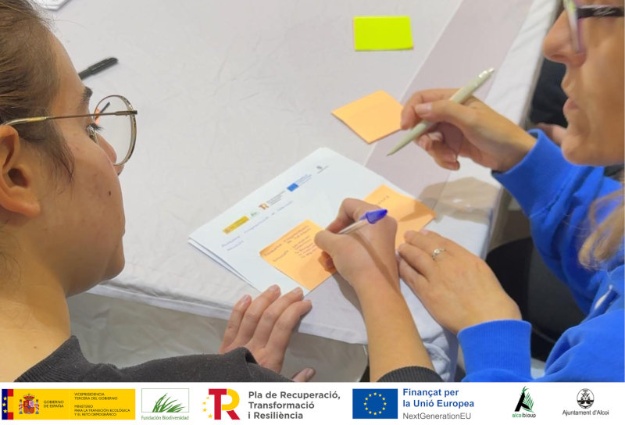 Dues persones prenent notes en una sessió participativa