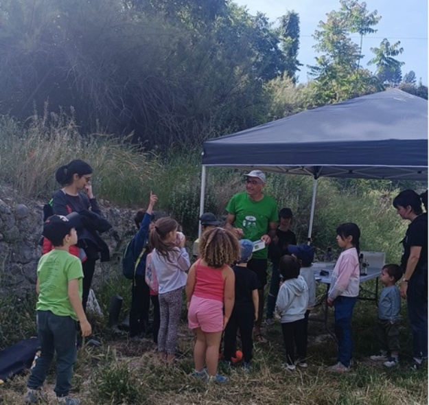 Niños y niñas atendiendo las explicaciones del profesor Santi Víllora bajo una carpa en el río Serpis