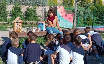 Xiquets i xiquetes al parc, asseguts en la gespa, escoltant l'educadora