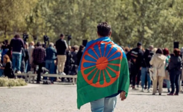 Persona con la bandera del pueblo gitano a la espalda