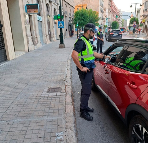Agent de policia local efectuant una prova d'alcoholèmia a un conductor dins del seu vehicle en un control de trànsit