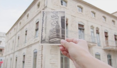 captura de pantalla del vídeo sobre el modernisme en el qual es veu una mà sostenint una foto antiga amb la Casa Escaló de fons