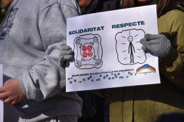 Mans d'una xiqueta agafant un cartell que posa Solidaritat i Respecte