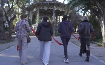 Captura del vídeo del Consell Social en el qual es veu a quatre dones d'esquena sostenint una cinta roja